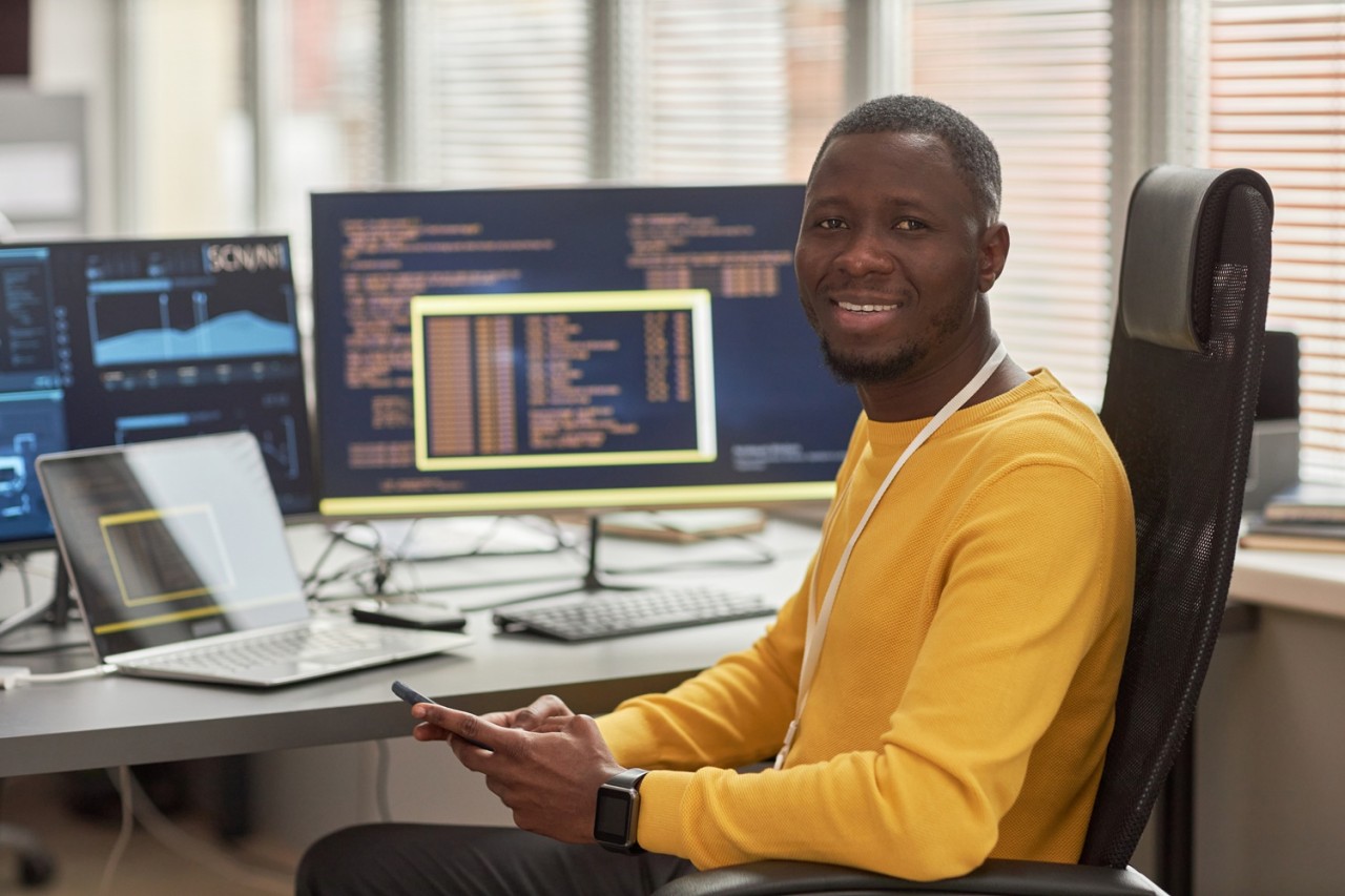 smiling-black-man-looking-at-camera-at-workplace-i-2025-03-09-09-40-35-utc